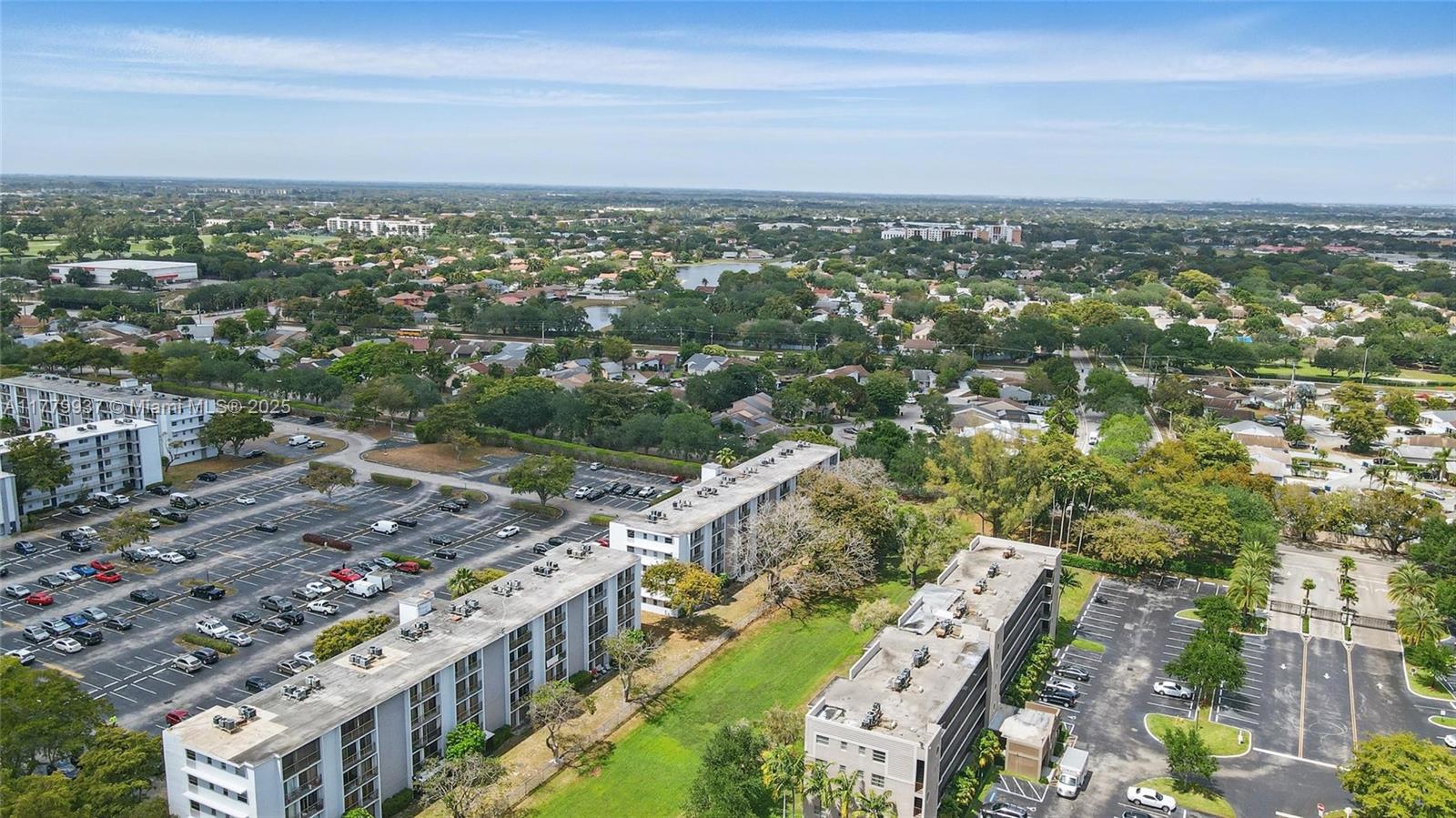 An aerial view shows several multi-story apartment buildings surrounded by parking lots and suburban greenery — 8540 N Sherman Cir # 408, Miramar FL 33025, MIRAMAR, FL
