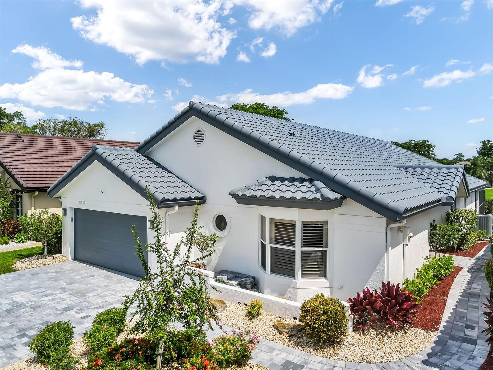 A white house with a gray tile roof, a two-car garage, and a paved driveway — 21089 Cottonwood Drive, Boca Raton FL 33428, BOCA RATON, FL