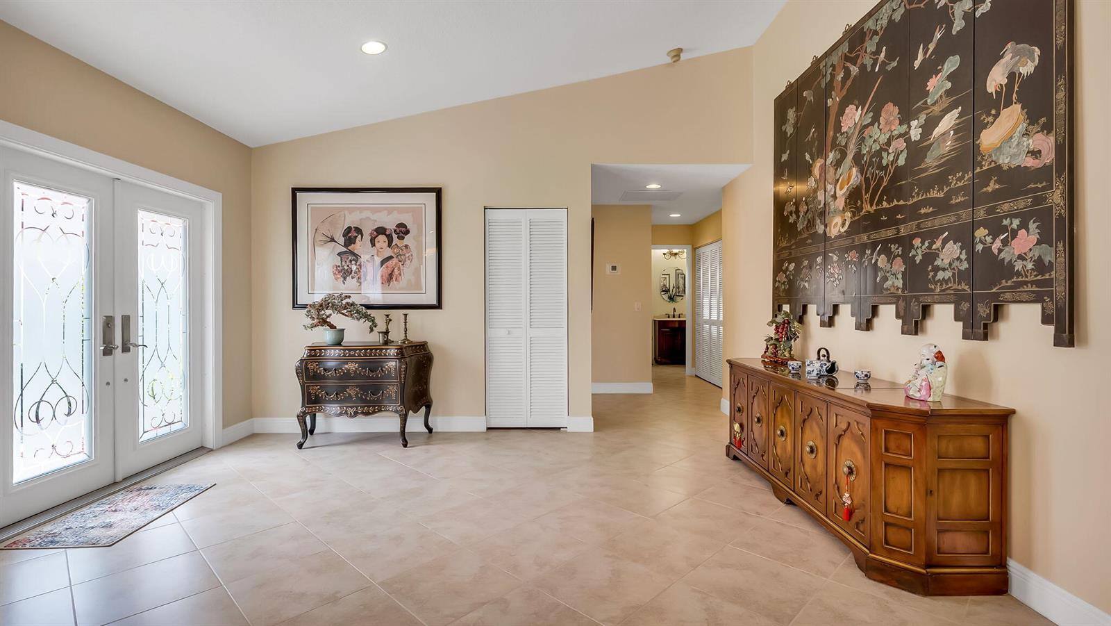 A tiled entryway features a double front door, two wooden cabinets, and Asian-inspired wall art — 21089 Cottonwood Drive, Boca Raton FL 33428, BOCA RATON, FL