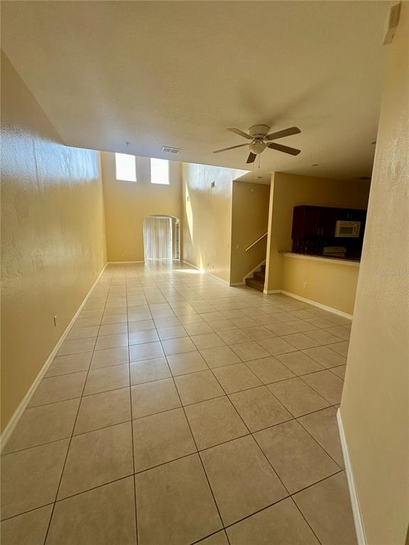 A spacious living area with high ceilings, tile flooring, and an adjacent kitchen — 6112 CHAPLEDALE DRIVE, ORLANDO, FL