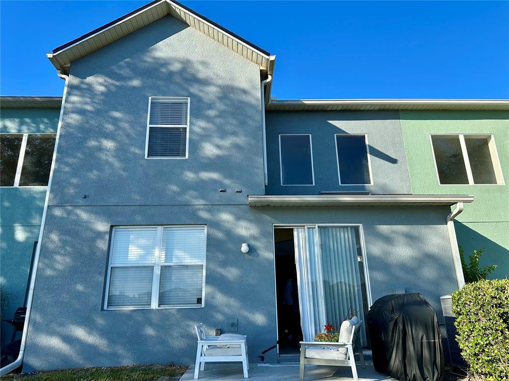 The rear exterior of a two-story townhouse features a concrete patio and sliding glass doors — 6112 CHAPLEDALE DRIVE, ORLANDO, FL