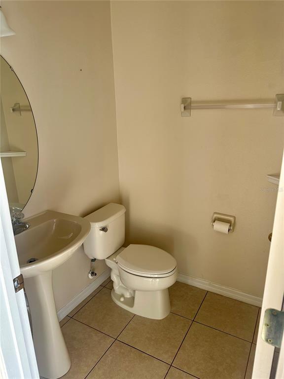 A small bathroom features a pedestal sink, a toilet, and beige tile flooring — 6112 CHAPLEDALE DRIVE, ORLANDO, FL