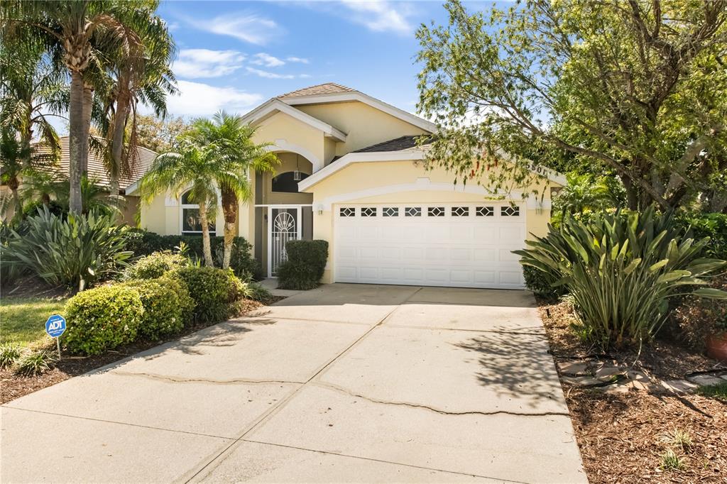 A single-story house with a yellow stucco exterior, a two-car garage, and lush landscaping — 6801 SUPERIOR STREET CIRCLE, SARASOTA, FL