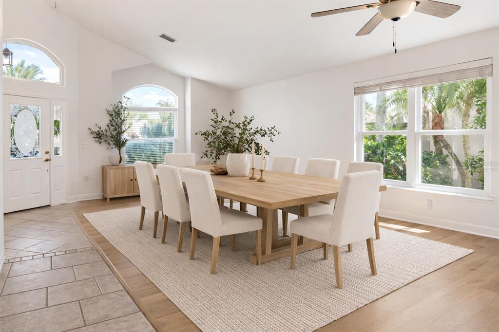 A dining room features a long wooden table, upholstered chairs, and large windows with greenery — 6801 SUPERIOR STREET CIRCLE, SARASOTA, FL