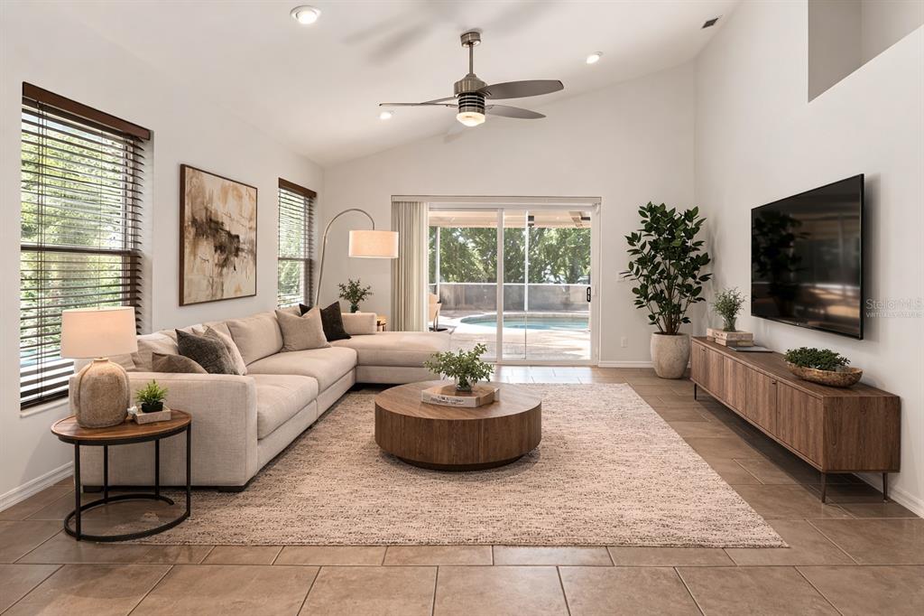 A living room features a sectional sofa, round coffee table, media console, and sliding glass doors — 6801 SUPERIOR STREET CIRCLE, SARASOTA, FL