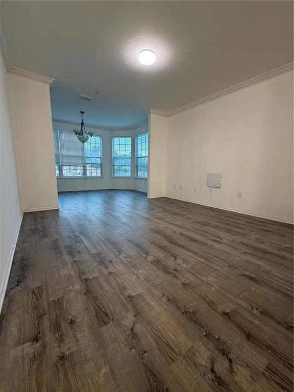 An empty living room with wood-look flooring, crown molding, and a bay window area — 3307 S KIRKMAN ROAD UNIT 123, ORLANDO, FL