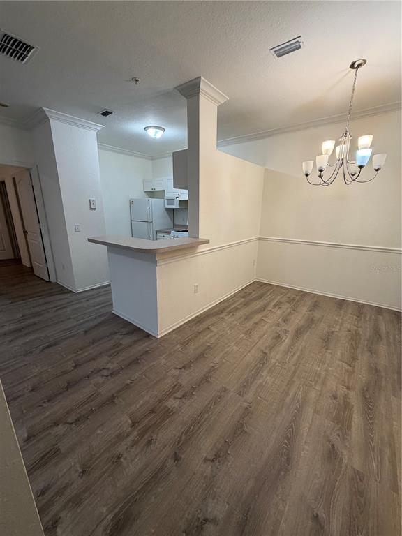 A dining area with wood-look flooring and a chandelier adjacent to a small kitchen — 3307 S KIRKMAN ROAD UNIT 123, ORLANDO, FL