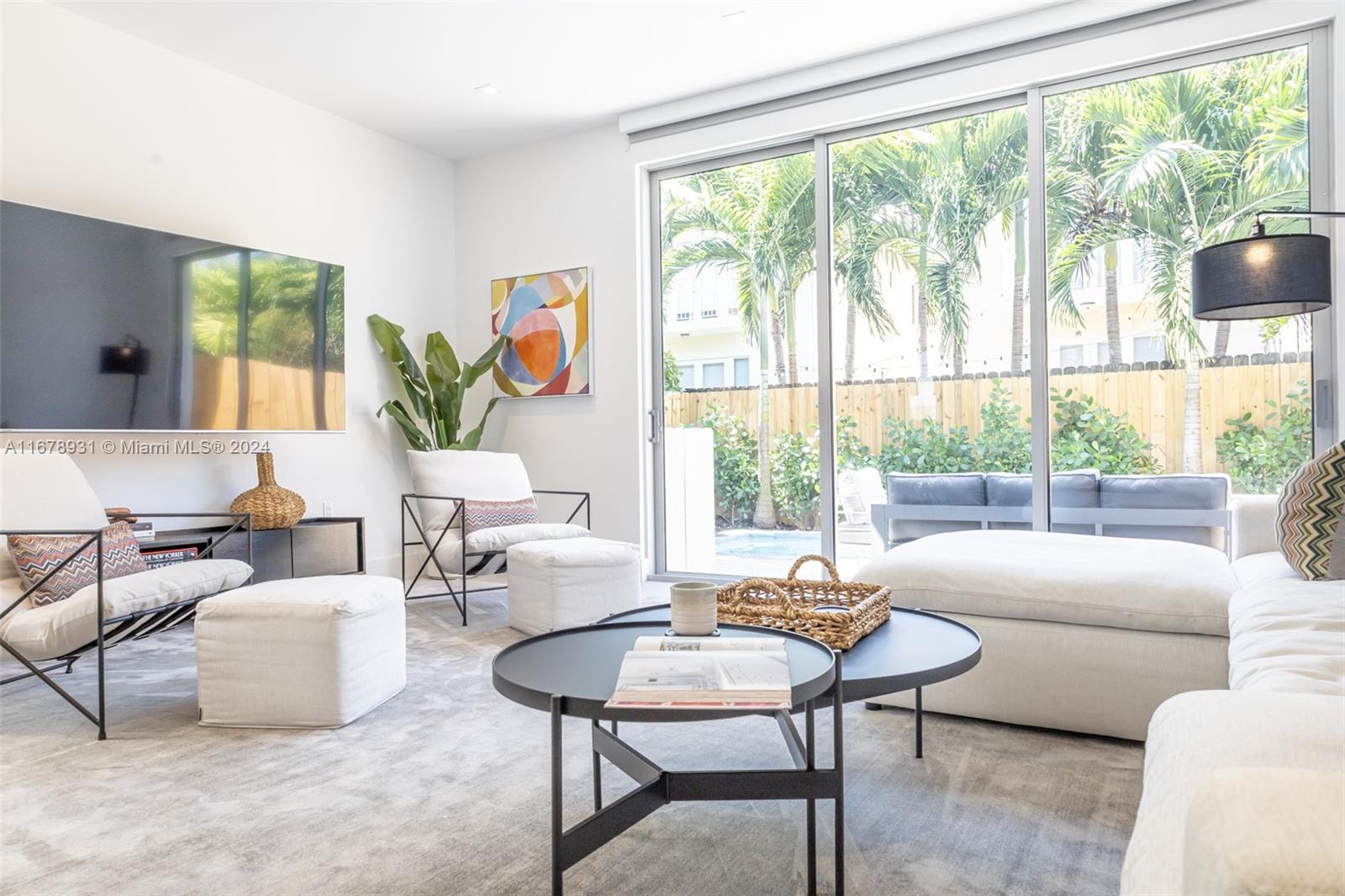 A bright living room features a large television, modern furniture, and sliding glass doors — 3110 Elizabeth St # 3110, Miami FL 33133, MIAMI, FL