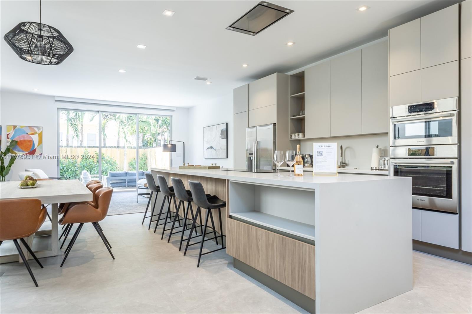 A modern kitchen features a large island with bar seating and light wood cabinetry — 3110 Elizabeth St # 3110, Miami FL 33133, MIAMI, FL