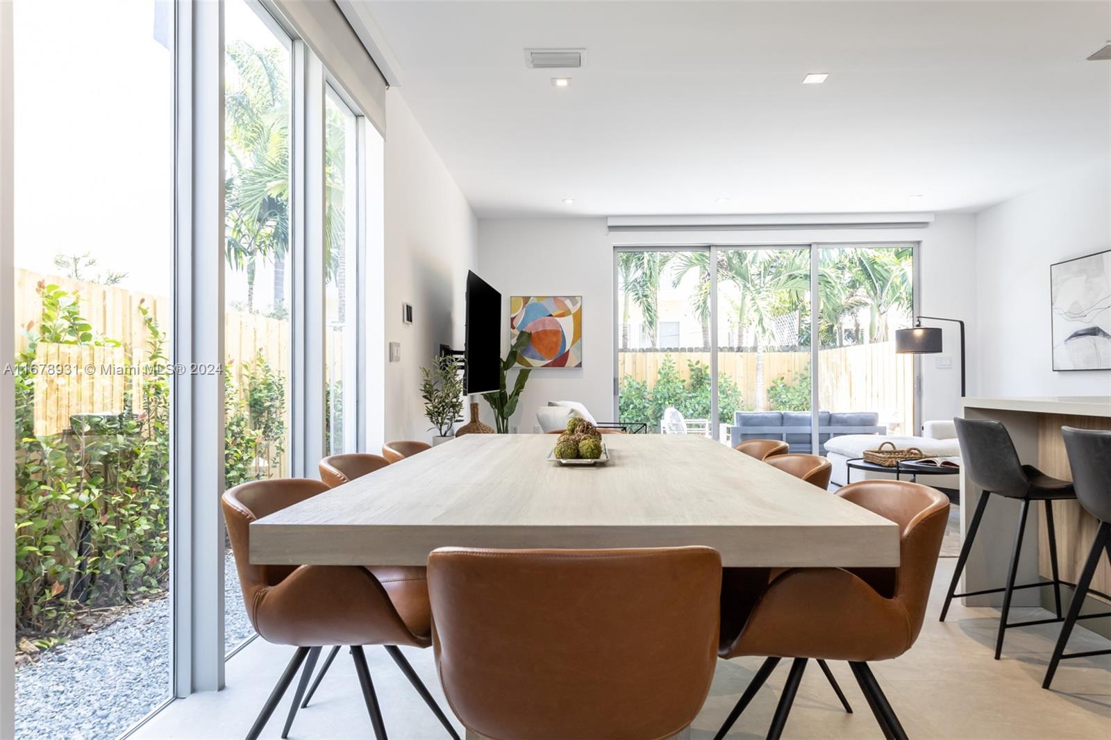 A dining room features a light wood table, tan leather chairs, and floor-to-ceiling glass doors — 3110 Elizabeth St # 3110, Miami FL 33133, MIAMI, FL