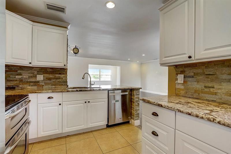 A kitchen features white cabinets, granite countertops, a stone backsplash, and stainless steel appliances — 9387 Richmond Circle, Boca Raton FL 33434, BOCA RATON, FL