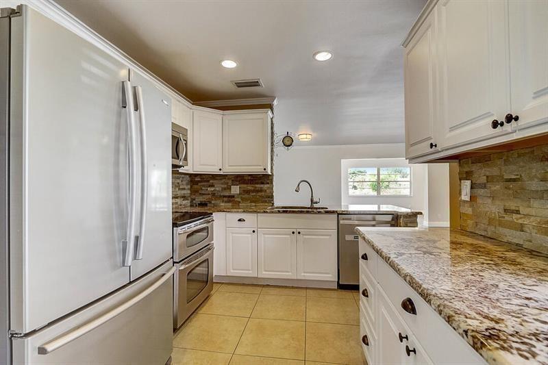 A kitchen features white cabinets, granite countertops, a stone backsplash, and stainless steel appliances — 9387 Richmond Circle, Boca Raton FL 33434, BOCA RATON, FL