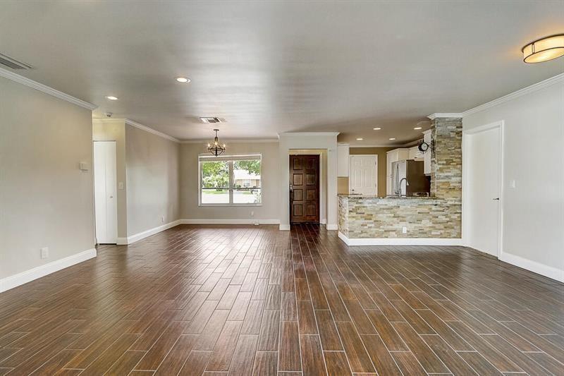 An open-concept living area features wood-look tile flooring, a stone-accented kitchen island, and recessed lighting — 9387 Richmond Circle, Boca Raton FL 33434, BOCA RATON, FL