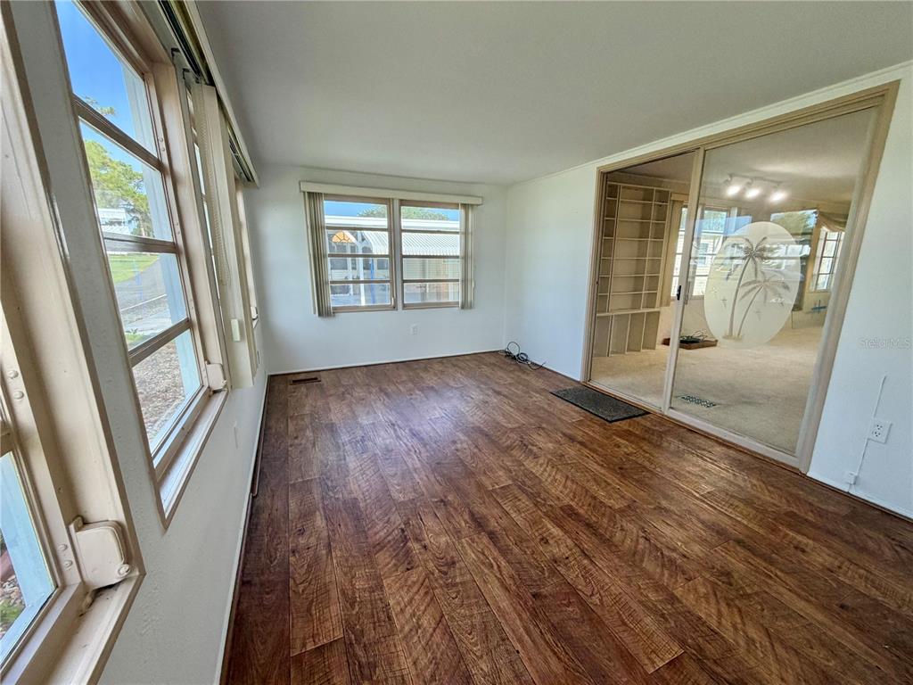 A sunroom features wood-look flooring, large windows, and a sliding glass door to another room — 416 PALO VERDE DRIVE, LEESBURG, FL