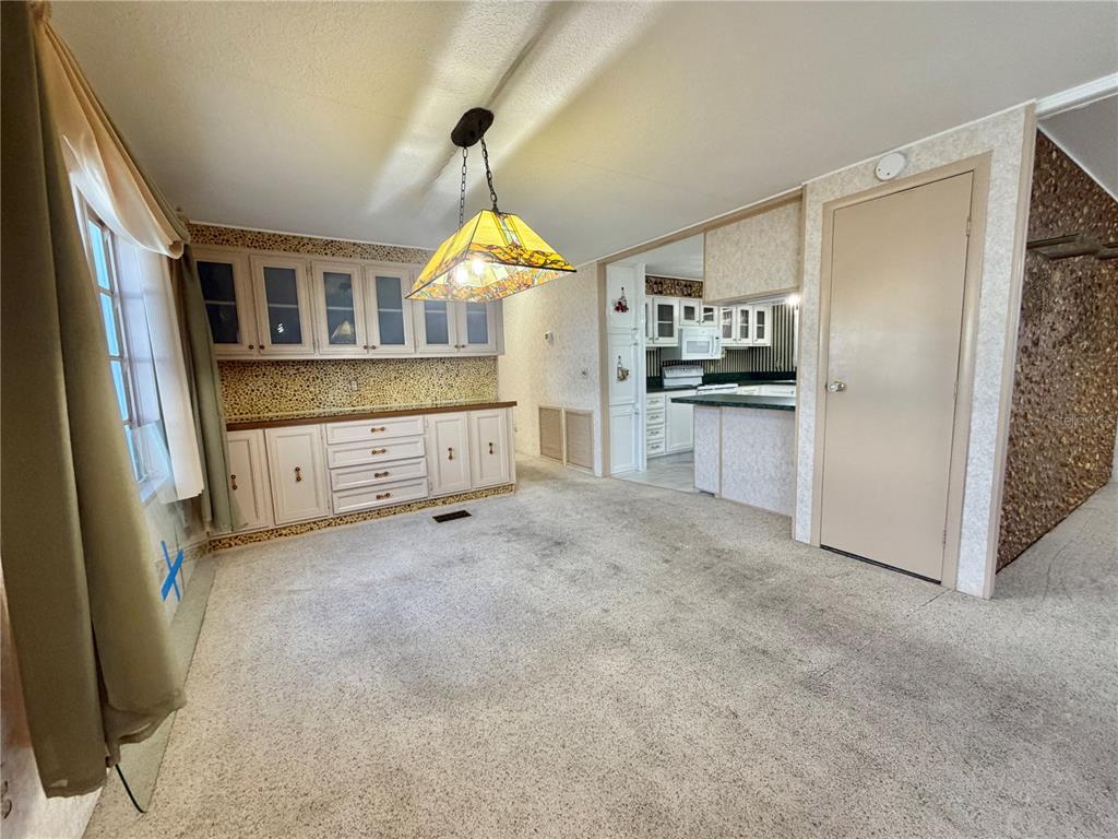 A dining area features carpeted floors, built-in cabinetry, a stained-glass pendant light, and wallpaper — 416 PALO VERDE DRIVE, LEESBURG, FL