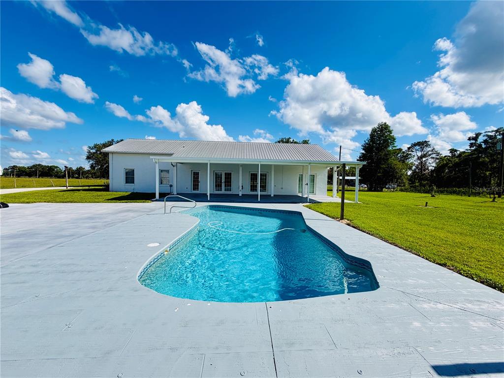 A white single-story house sits in the middle of a large, grassy field — 9120 COUNTY ROAD 304, BUNNELL, FL