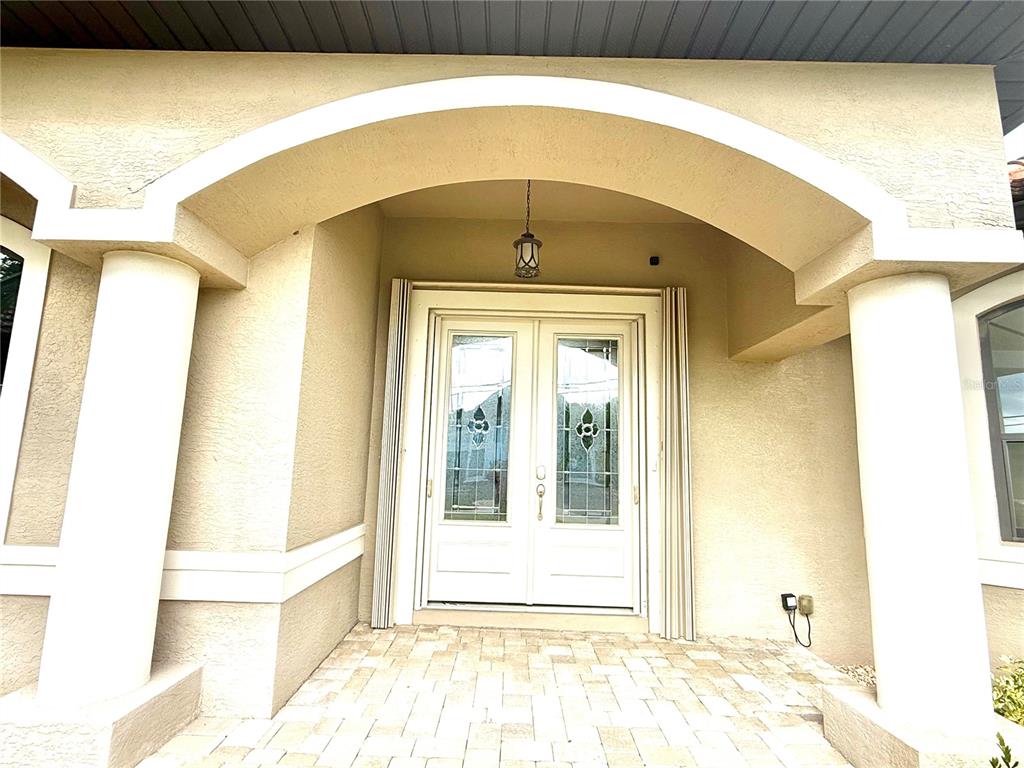 A covered entryway features double glass-paneled doors, white columns, and a paved stone floor — 2736 MAGDALINA DRIVE, PUNTA GORDA, FL