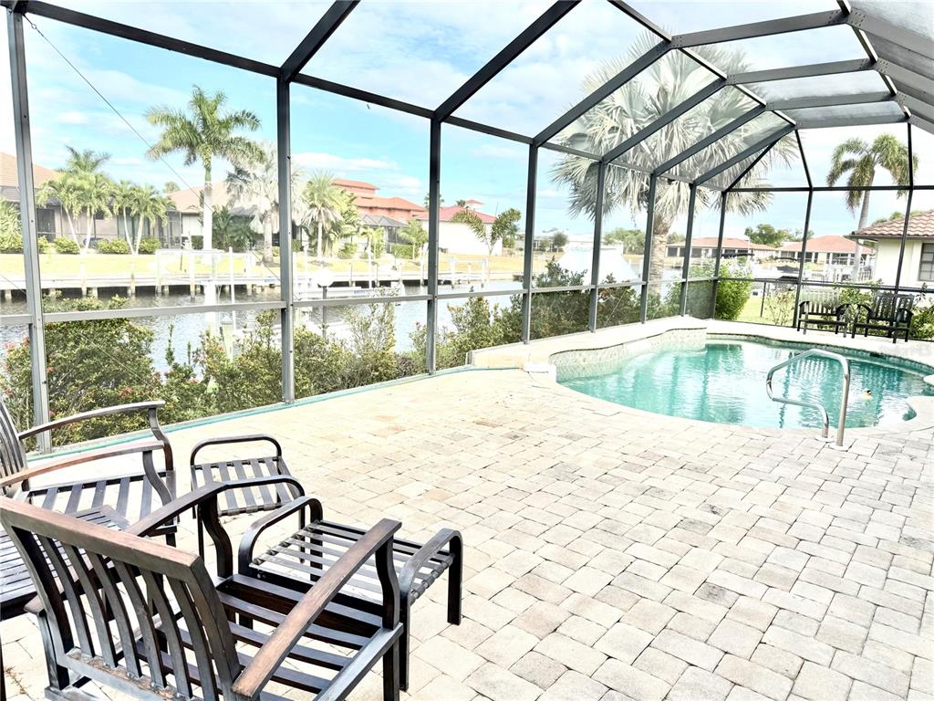 A screened-in patio features a paved deck, a swimming pool, and a canal view — 2736 MAGDALINA DRIVE, PUNTA GORDA, FL
