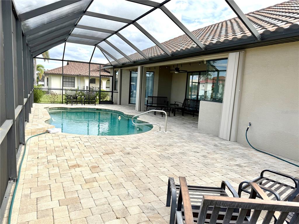 A screened-in patio features a swimming pool, paver flooring, and outdoor seating — 2736 MAGDALINA DRIVE, PUNTA GORDA, FL