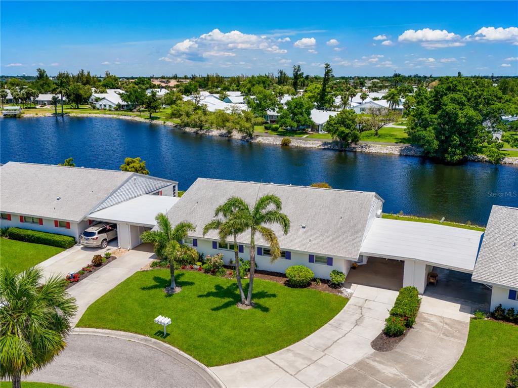 An aerial view shows a single-story house with a carport and lawn beside a lake — 4603 LEXINGTON CIRCLE, BRADENTON, FL