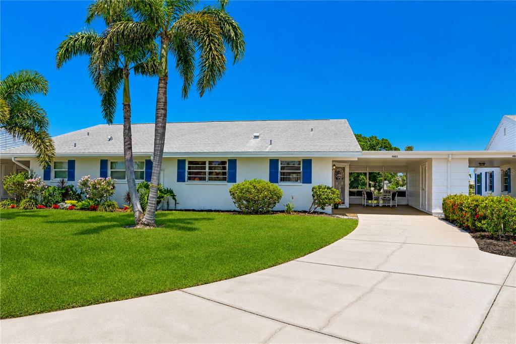 A single-story white house with blue shutters, a palm tree, and a concrete driveway — 4603 LEXINGTON CIRCLE, BRADENTON, FL