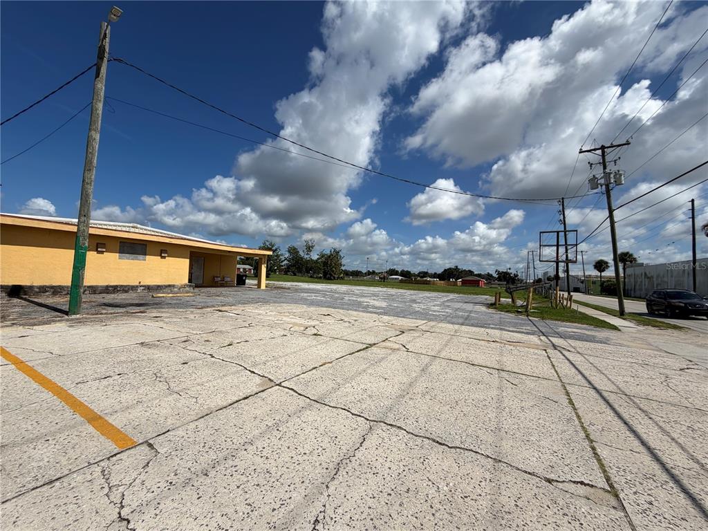 A yellow building stands next to a large, cracked concrete parking lot under a blue sky — 540 S SCENIC HIGHWAY, FROSTPROOF, FL