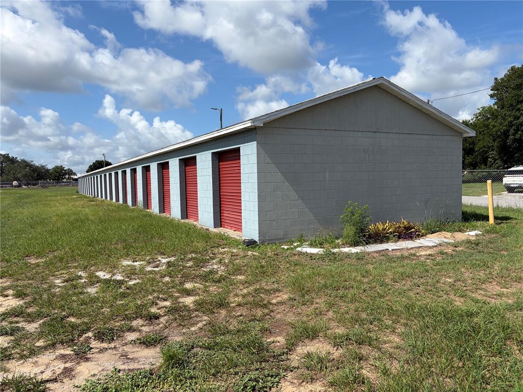 A long, single-story storage facility with grey concrete block walls and multiple red roll-up doors — 540 S SCENIC HIGHWAY, FROSTPROOF, FL