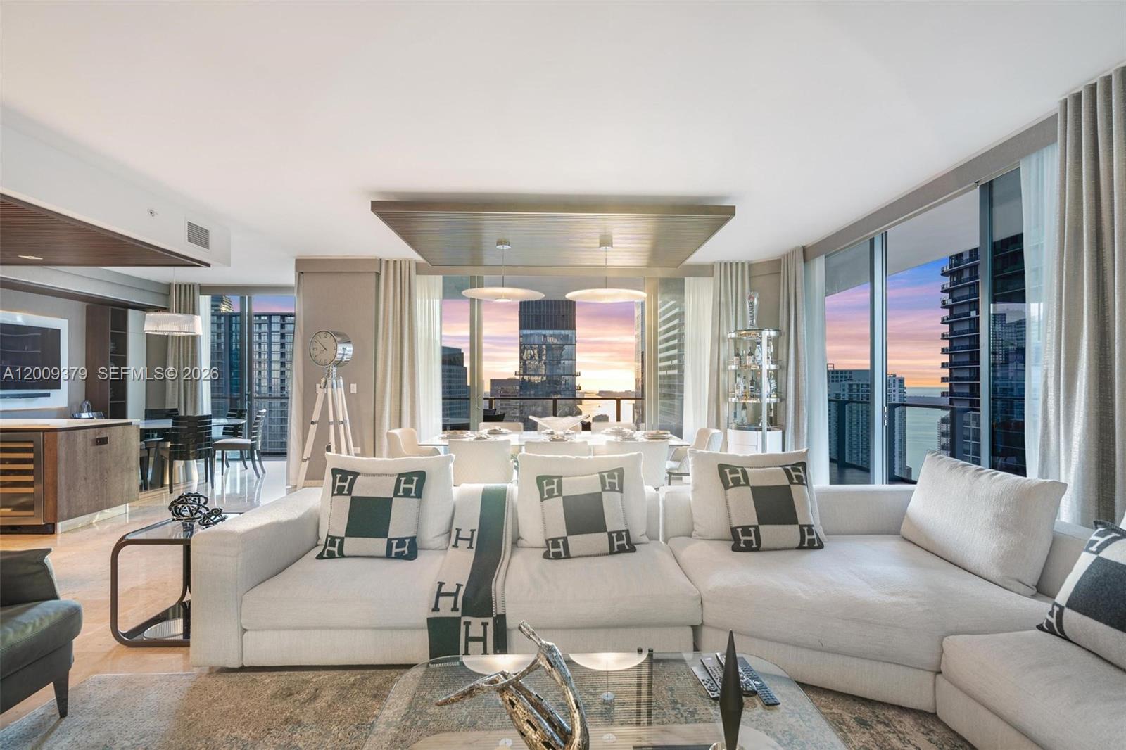 A modern living room features a white sectional sofa, dining area, and floor-to-ceiling windows — 88 SW 7th St # 3801, Miami FL 33130, MIAMI, FL