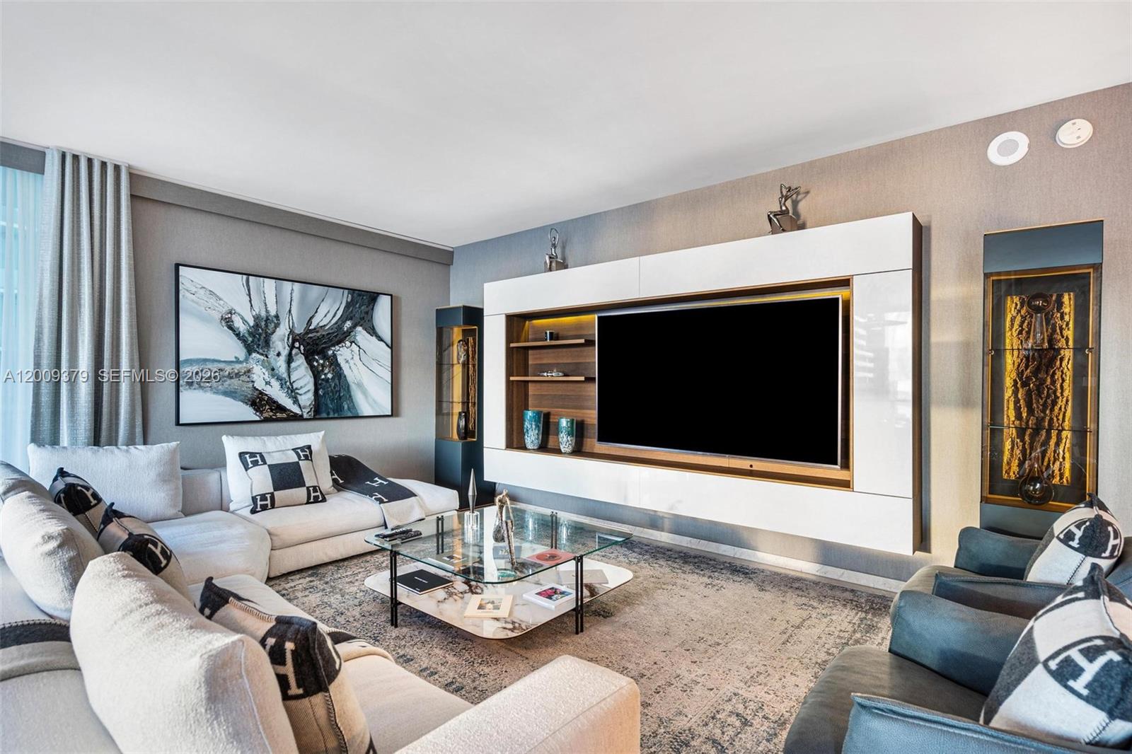 A modern living room features a large wall-mounted television, a glass coffee table, and sofas — 88 SW 7th St # 3801, Miami FL 33130, MIAMI, FL