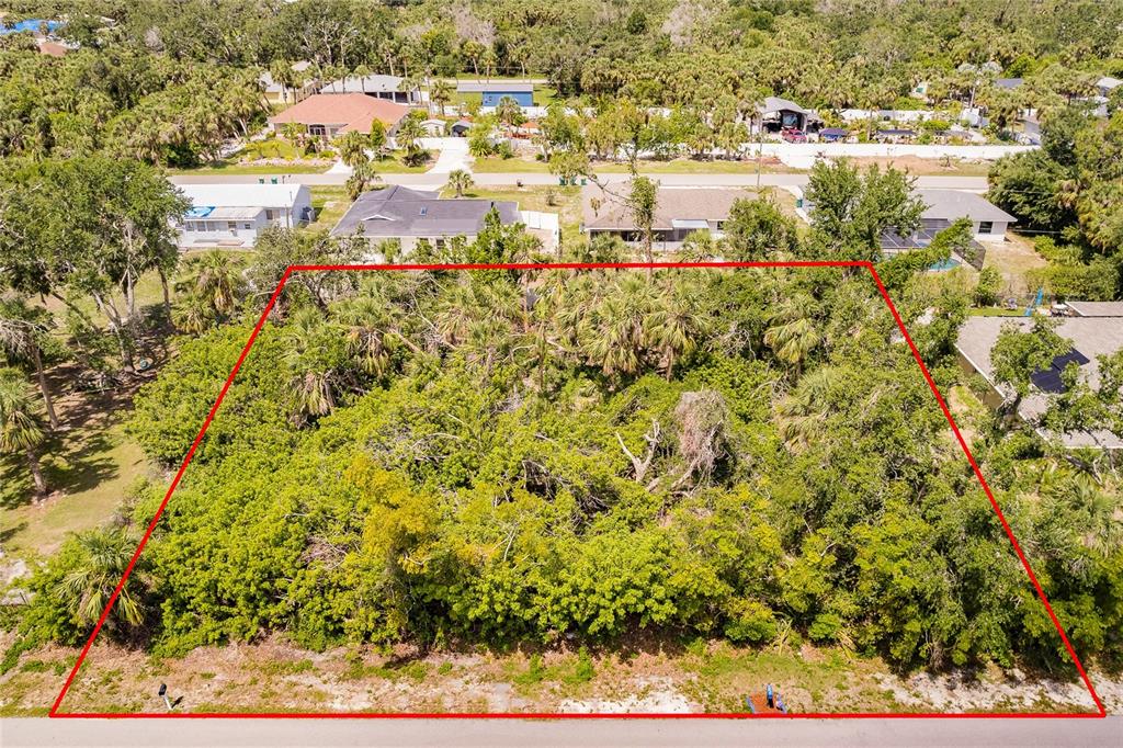 An aerial view shows a rectangular, wooded vacant lot outlined in red along a paved road — 2113 WONDERWIN STREET, PORT CHARLOTTE, FL