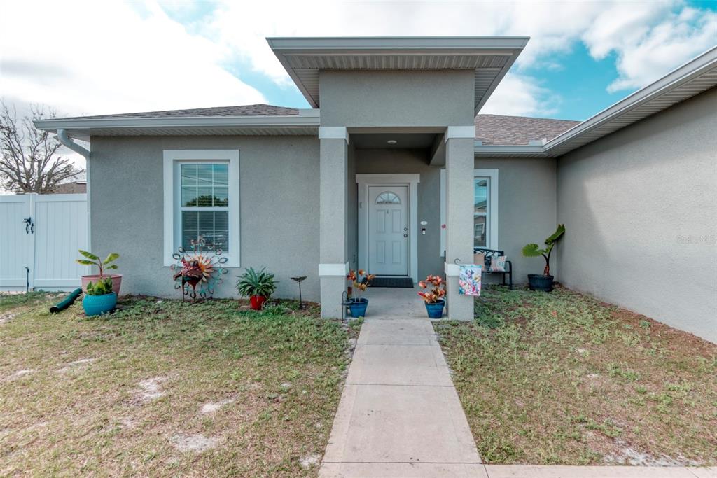 A single-story house with a gray stucco exterior, a covered entryway, and a concrete walkway — 125 INCONNU COURT, KISSIMMEE, FL