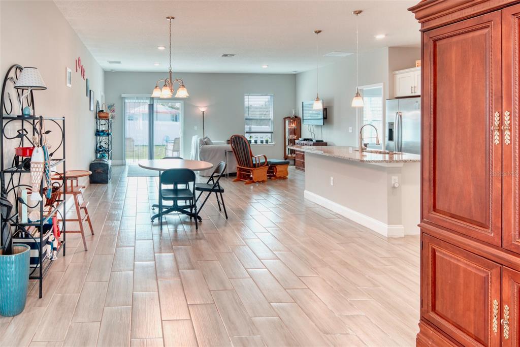 An open-concept living and dining area features light wood-look tile flooring and a kitchen island — 125 INCONNU COURT, KISSIMMEE, FL