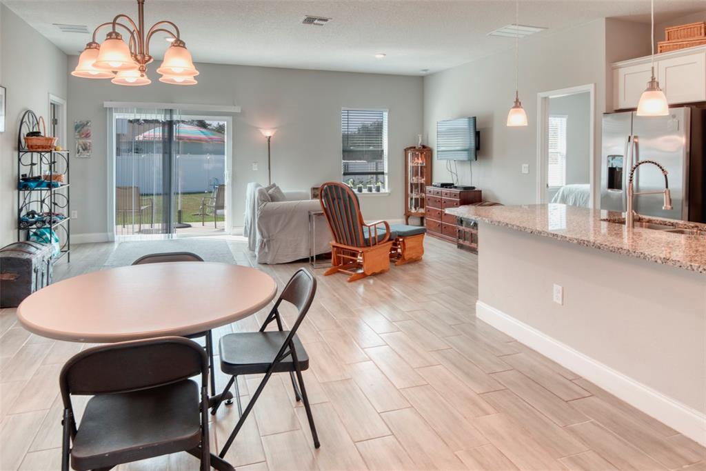 An open-concept living and dining area features tile flooring, a kitchen island, and sliding doors — 125 INCONNU COURT, KISSIMMEE, FL