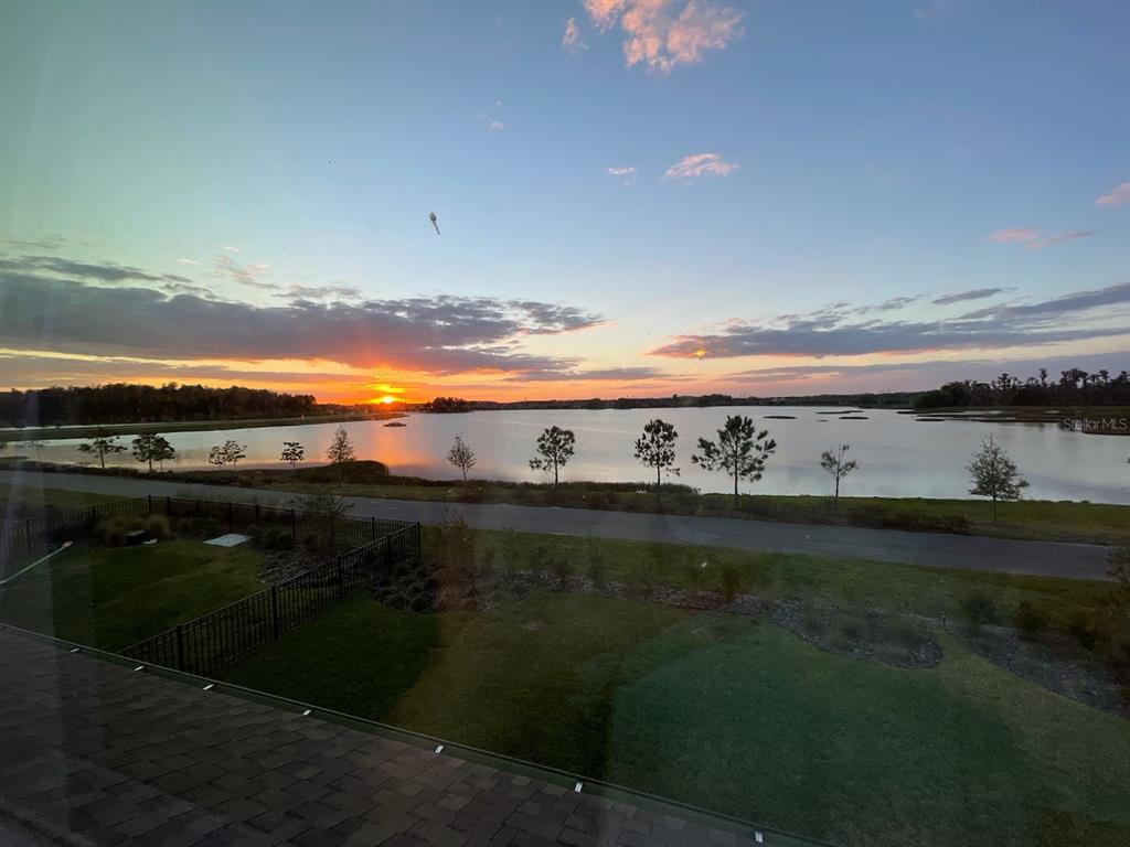 A view of a sunset over a lake from an elevated outdoor space — 3323 MONROE MEADOWS DRIVE, ODESSA, FL