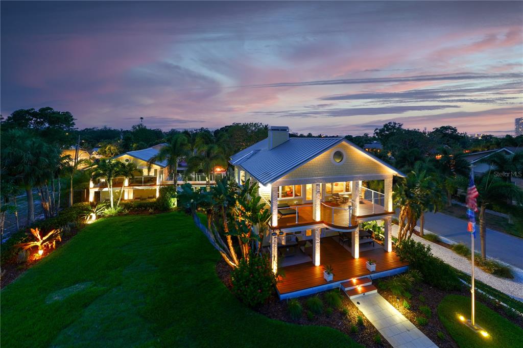 An elevated two-story house with a metal roof and wrap-around decks at twilight — 1803 BEACH DRIVE SE, ST PETERSBURG, FL
