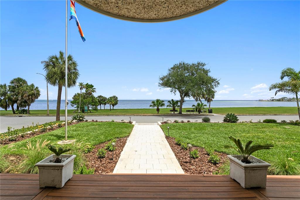 A view from a wooden porch looking out over a lawn toward the ocean — 1803 BEACH DRIVE SE, ST PETERSBURG, FL