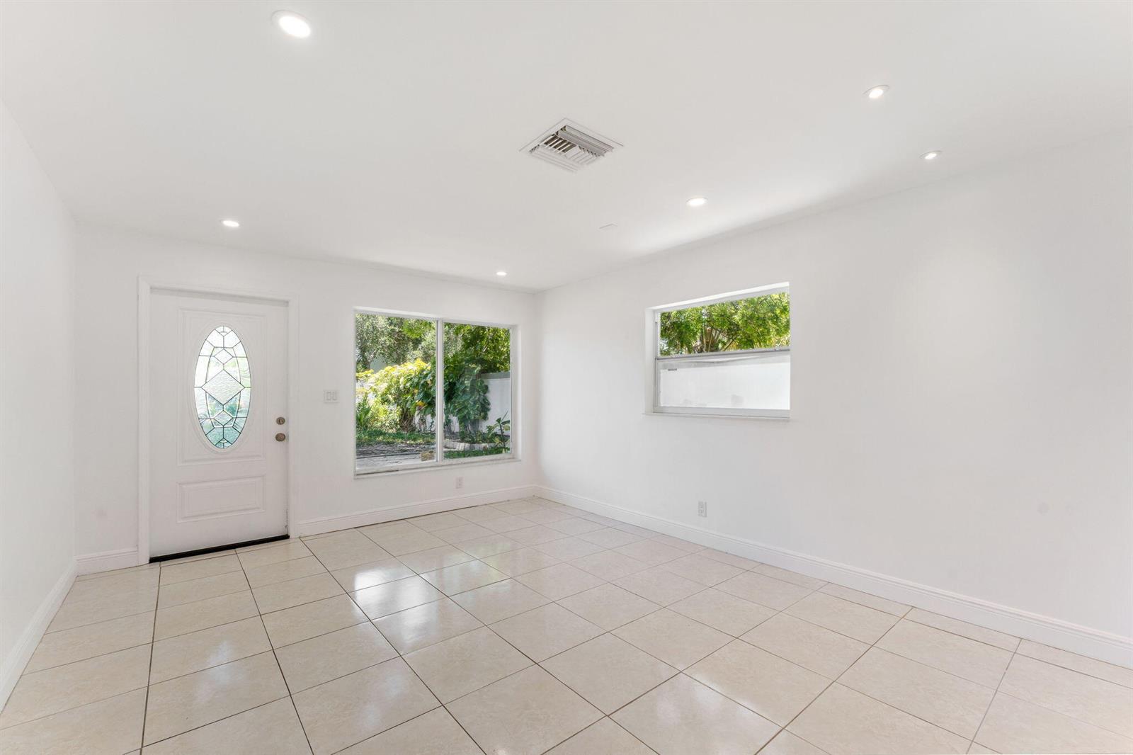An empty room with white walls, tile flooring, a front door, and two windows — 441 NW 1st Way, Deerfield Beach FL 33441, DEERFIELD BEACH, FL