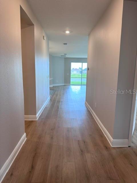 A hallway with wood-look tile flooring leads toward an open living area with sliding doors — 3550 74TH AVENUE CIRCLE E, SARASOTA, FL
