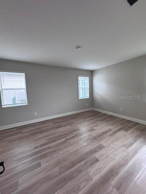 An empty room features light gray walls, two windows, and wood-look flooring — 3550 74TH AVENUE CIRCLE E, SARASOTA, FL