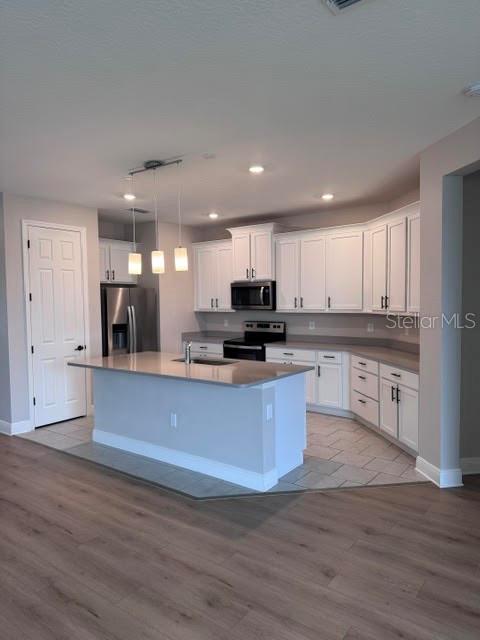 A kitchen features white cabinets, a central island, stainless steel appliances, and tile flooring — 3550 74TH AVENUE CIRCLE E, SARASOTA, FL