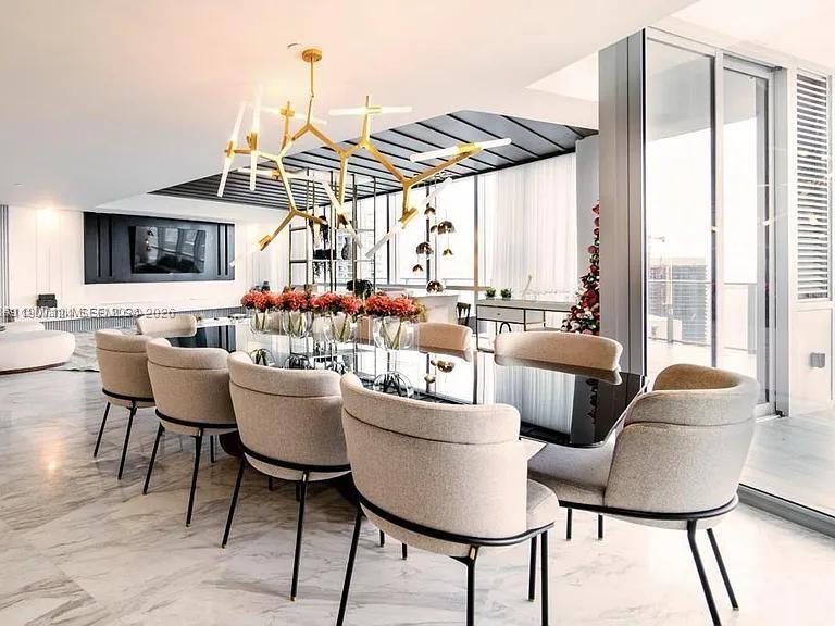 A modern dining room features a glass table, upholstered chairs, and a unique gold chandelier — 851 NE 1st Ave # 4811, Miami FL 33132, MIAMI, FL