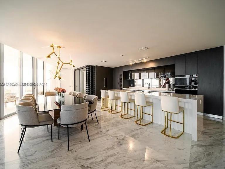 A modern kitchen and dining area features marble floors, dark cabinetry, and gold-accented lighting — 851 NE 1st Ave # 4811, Miami FL 33132, MIAMI, FL