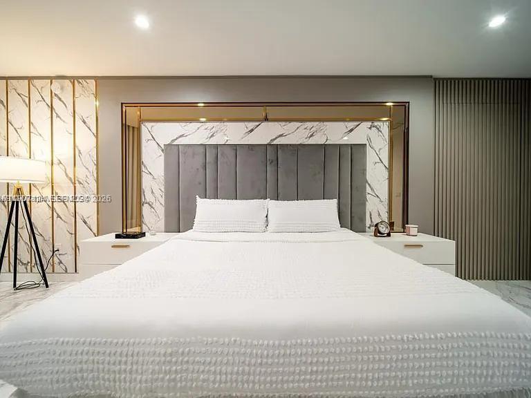 A bedroom features a tufted gray headboard, marble-patterned wall panels, and white bedside tables — 851 NE 1st Ave # 4811, Miami FL 33132, MIAMI, FL