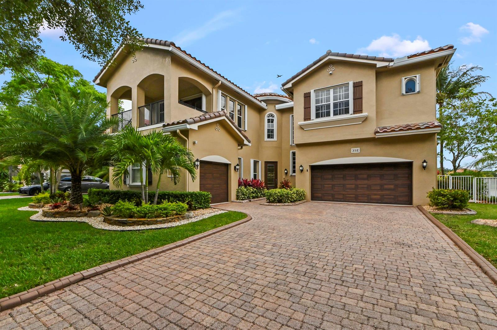A two-story tan stucco house features a paved driveway, two garages, and a balcony — 458 Cresta Circle, West Palm Beach FL 33413, WEST PALM BEACH, FL