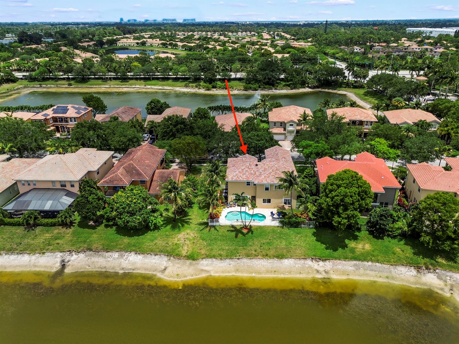An aerial view shows a two-story house with a backyard pool overlooking a lake — 458 Cresta Circle, West Palm Beach FL 33413, WEST PALM BEACH, FL