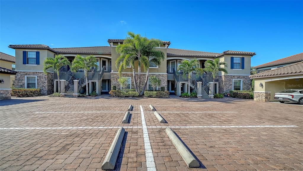 A two-story apartment building with a paved parking lot and palm trees in front — 13604 MESSINA LOOP UNIT 103, LAKEWOOD RANCH, FL