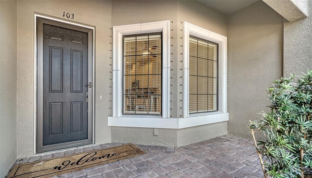 A front entrance with a dark door, two windows, and a paved porch area — 13604 MESSINA LOOP UNIT 103, LAKEWOOD RANCH, FL