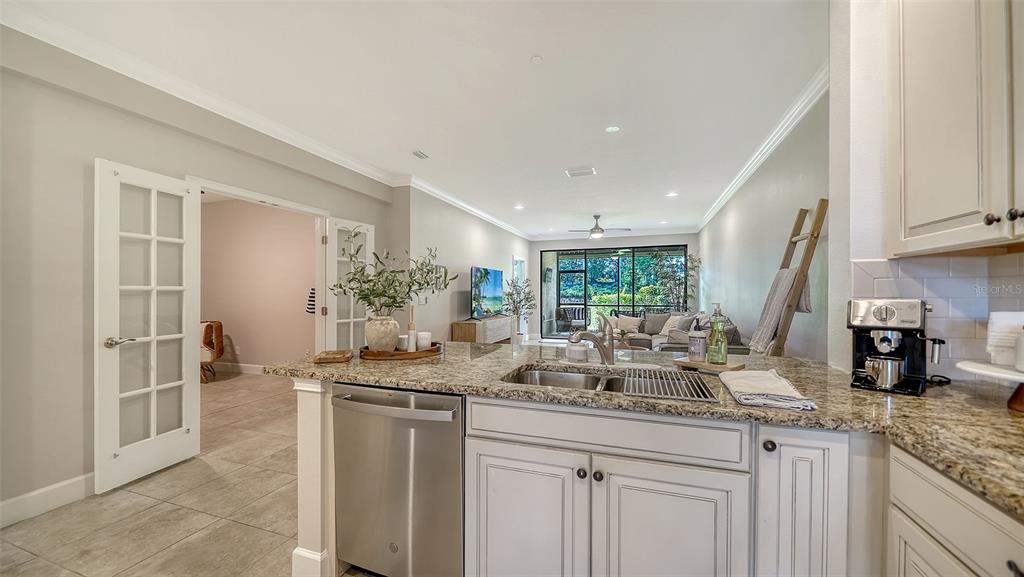 A kitchen with granite countertops and stainless steel appliances overlooks an open-concept living area — 13604 MESSINA LOOP UNIT 103, LAKEWOOD RANCH, FL