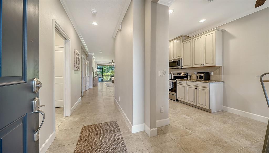 A view from an entryway looking toward a kitchen and a hallway with tile flooring — 13604 MESSINA LOOP UNIT 103, LAKEWOOD RANCH, FL