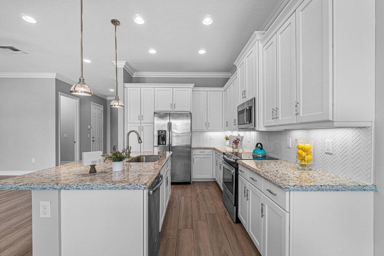 A modern kitchen features white cabinets, granite countertops, stainless steel appliances, and a central island — 14131 Rock Salt Road, Delray Beach FL 33446, DELRAY BEACH, FL